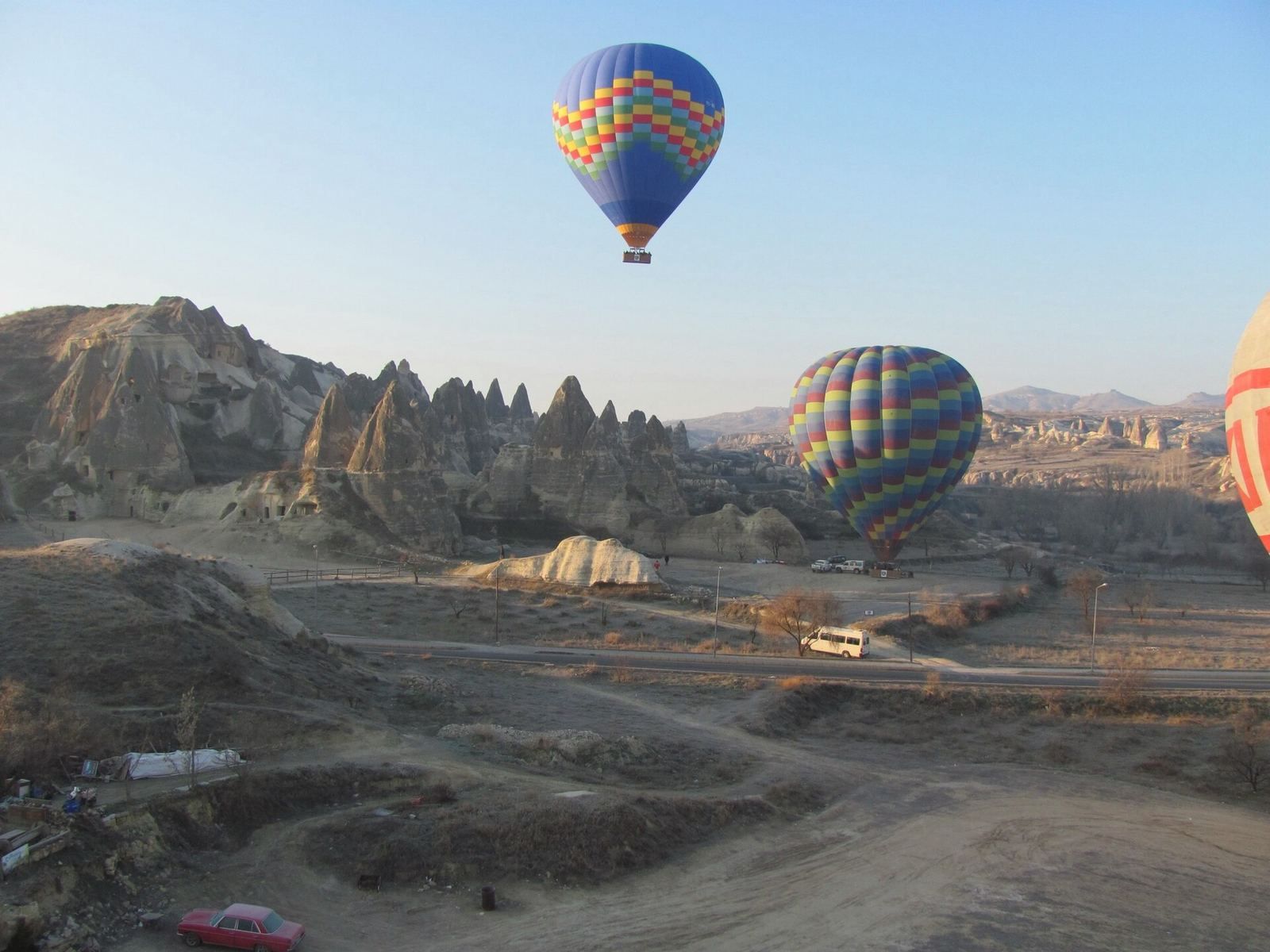 Balony schodzą do lądowania nad drogą w Kapadocji, na dole czeka ekipa naziemna