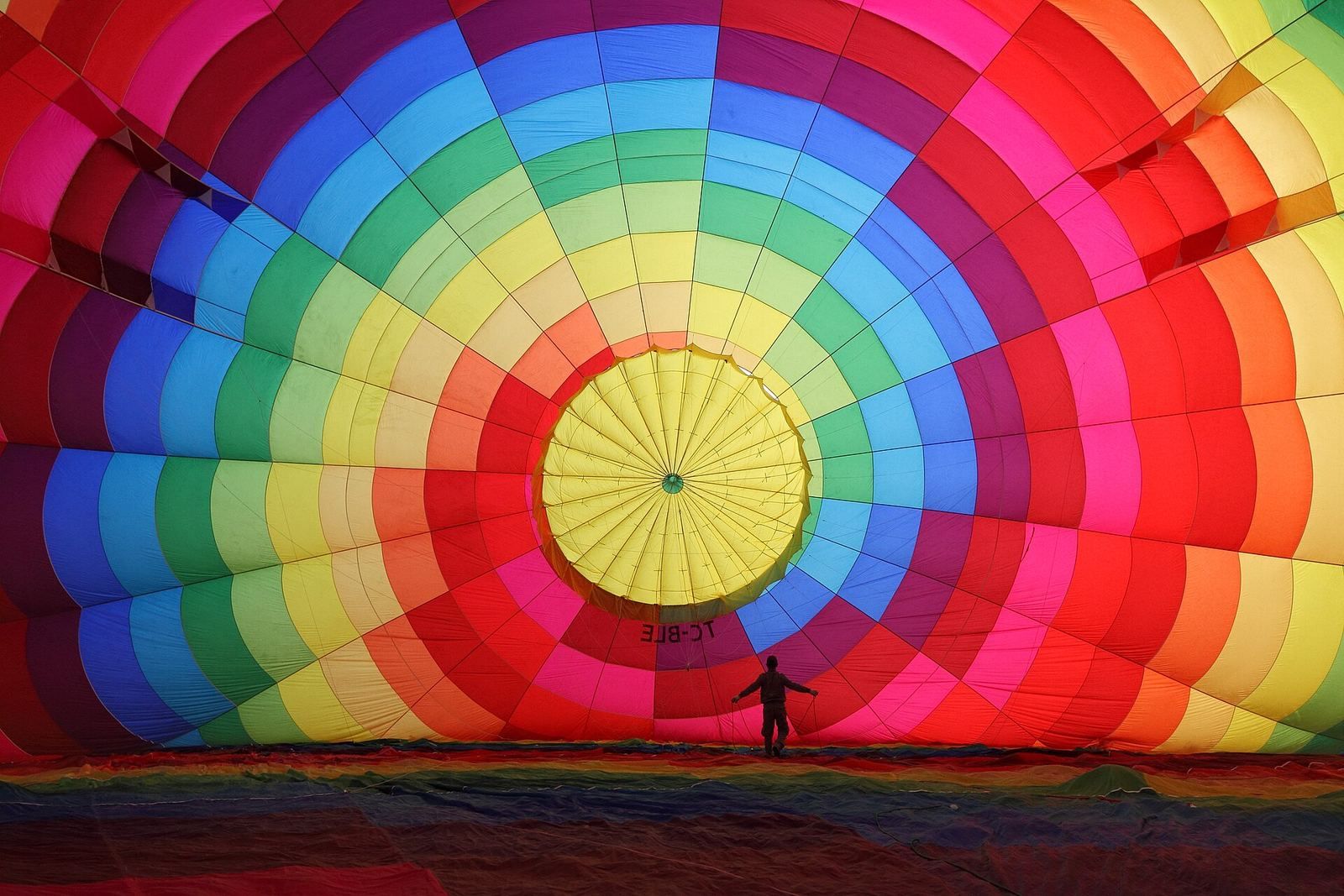 Napełnianie powłoki balonu zimnym powietrzem przed startem, pasażerowie czekają na polu startowym