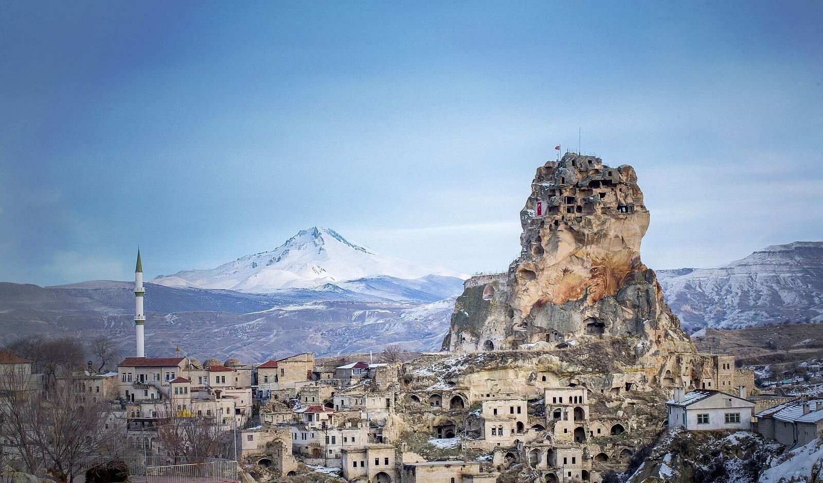 Skalny zamek Ortahisar z ośnieżonym wulkanem Erciyes w tle